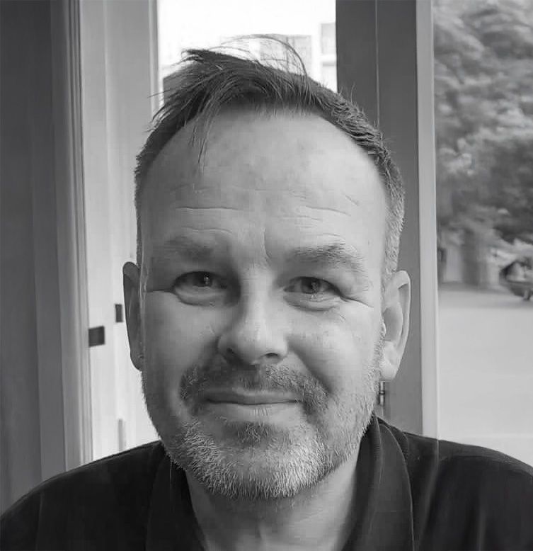 A black and white photo of a smiling man, showcasing his joyful expression and friendly demeanor.