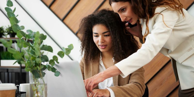 Two women collaborating on a laptop, engrossed in their work.