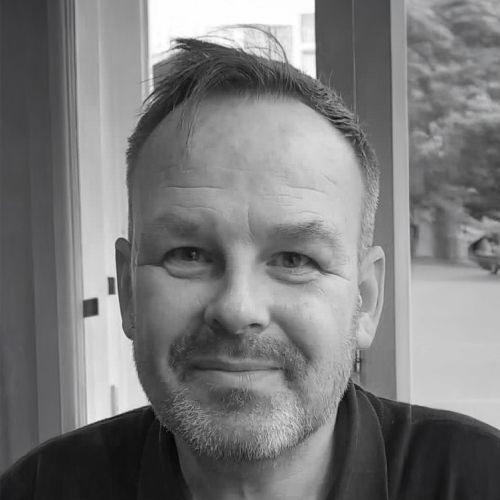 A black and white photo of a smiling man, showcasing his joyful expression and friendly demeanor.