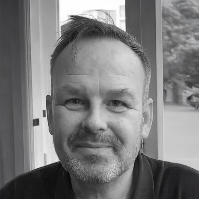 A black and white photo of a smiling man, showcasing his joyful expression and friendly demeanor.