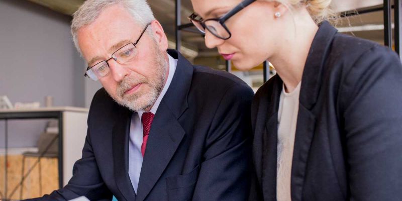 A man and woman in business attire reviewing paperwork together, discussing important documents.